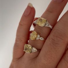 a woman's hand with three rings on her fingers and two yellow diamonds in the middle