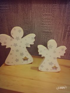 two wooden cut out angels sitting on top of a table