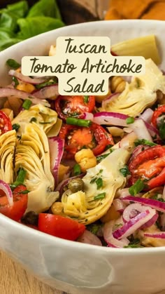 a white bowl filled with pasta and vegetables on top of a wooden table next to lettuce