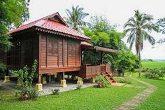 a small wooden house sitting in the middle of a lush green field next to trees