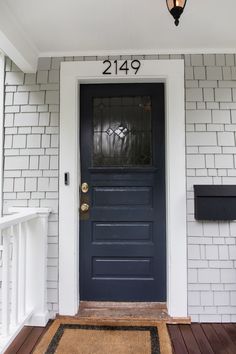 the front door is painted dark blue and has a welcome mat in front of it