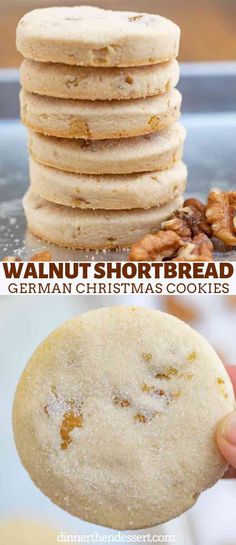 a stack of shortbread cookies with walnuts on top and in the background, there is a hand holding a cookie