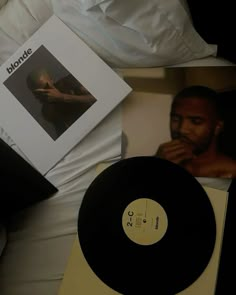 a record player sitting on top of a bed next to a photo and album cover