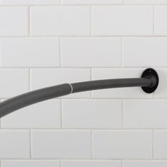 a black shower handle on a white tiled wall