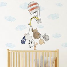 a baby's room with a crib and wall decal featuring animals flying in the sky