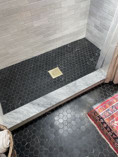 a tiled shower stall with a rug on the floor