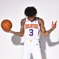 a man holding a basketball in his right hand and wearing white shorts with orange trim