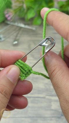 someone is knitting something green with a pair of scissors