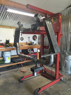 a large metal object sitting on top of a red stand in a garage next to other tools