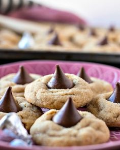 chocolate chip cookies on a pink plate with other cookies in the background