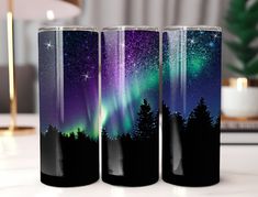 three glass tumbles with the image of an aurora bore and stars in the sky