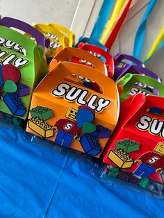 many colorful boxes with legos on them sitting on a blue tablecloth covered table