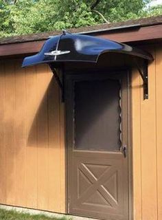 an outside view of a shed with a door and umbrella over the entrance to it