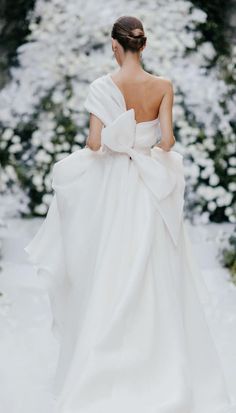 a woman in a white dress walking down a snow covered path with her back to the camera