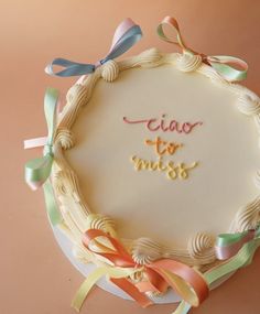 a cake decorated with ribbons and the words ciao to miss on it's side