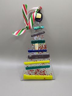 a christmas tree made out of different colored pieces of glass and ribbons on top of each other