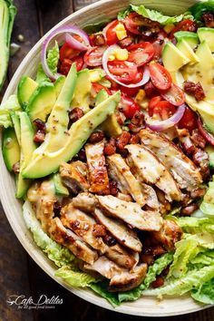 a salad with chicken, lettuce, tomatoes and avocado on it