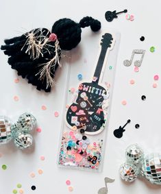 a black and white guitar shaped keychain surrounded by confetti