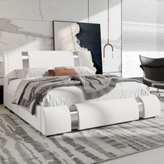 a white bed sitting on top of a rug next to a black chair and table