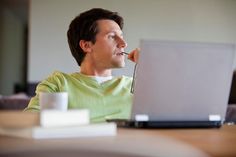 a man sitting at a table with a laptop computer in front of him and looking off to the side