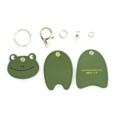 three pieces of luggage with keyrings and two frog shaped tags attached to them