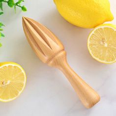 a wooden fork next to lemons on a white counter with greenery in the background