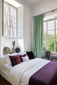 a bedroom with a large bed and green drapes on the window sill above it