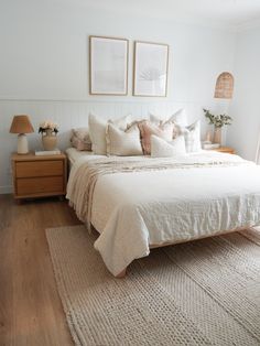 a white bed sitting in a bedroom on top of a wooden floor next to two framed pictures