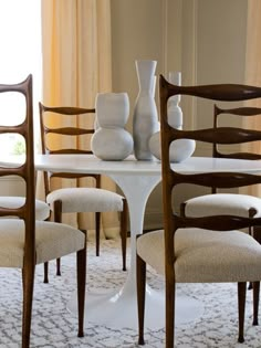 a dining room table with chairs and vases on it