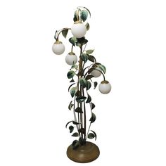 a tall metal plant with white balls on it's top and green leaves around the base