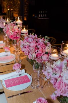 the table is set with pink flowers, candles and place settings for an elegant dinner