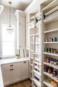 a kitchen with white cabinets and shelves filled with food