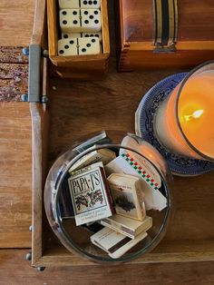 a candle and some dices in a box on a table with other items around it