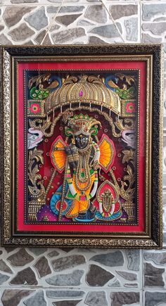 an ornately decorated ganesha painting hanging on the wall in front of a stone wall