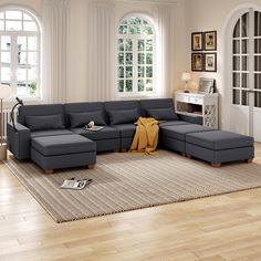 a living room with a large sectional couch and rugs on the wooden flooring