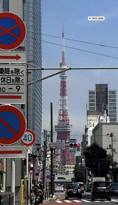 street signs and traffic lights in front of a tall building with a spire behind it