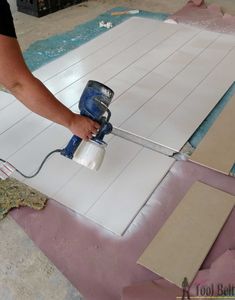 a person using a paint roller on the floor in front of some boards and tiles