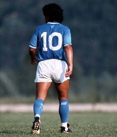 a soccer player in blue and white uniform standing on the field with his back to the camera