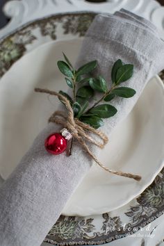 the napkin is tied with twine and has a red ornament on it