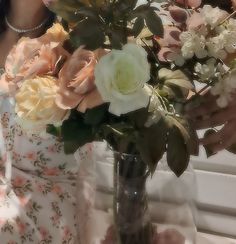 a vase filled with white and pink flowers on top of a table next to a window