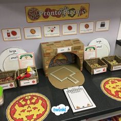 a table topped with lots of pizzas and paper plates on top of it's counter