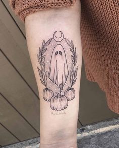 a person with a tattoo on their arm that has an image of a ghost and pumpkins