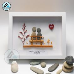 two people sitting on a bench surrounded by rocks and stones in a shadow box with the words happy 50th wedding anniversary