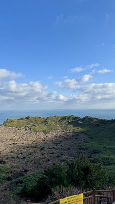 there is a bench on the top of a hill overlooking the ocean and hills in the distance