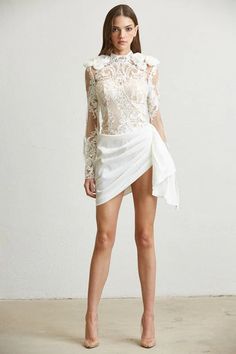 The "Baroque #Beauty Lace Mini #Dress" exudes an air of sophistication and #elegance. It is masterfully crafted with intricate lace detailing and features sheer sleeves and floral appliqués that enhance its #luxurious appeal. The #dress combines a classic baroque #style with a #modern asymmetrical skirt, making it a stunning choice for any high-end social event or party. Mini Skirt Party, Skirt Draping, Casual Beach Wear, Classic Romance, Contemporary Chic, Satin Skirt, Sheer Sleeves, Lace Mini Dress, White Mini Dress