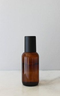 a brown glass bottle sitting on top of a white counter next to a black cap