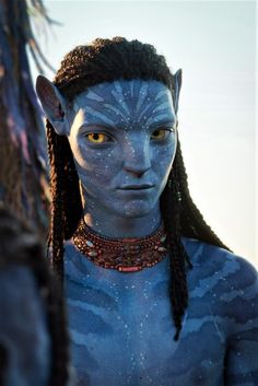 a man with blue makeup and braids standing next to another person in the background