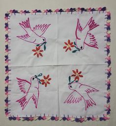 two white embroidered napkins with pink and purple flowers on them, one has a humming bird in the center