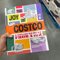 the joy of costco book is being held up by a person's hand