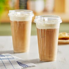 two iced coffees sitting on top of a table next to a plate of cookies